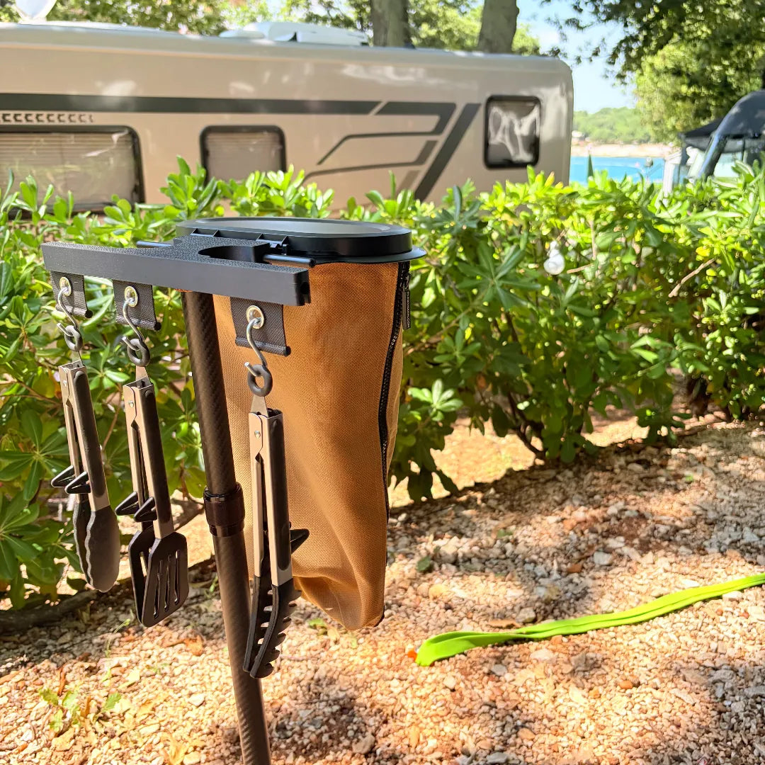 SheltaFlex FlexDock Duo auf einem Camping-Stellplatz mit Flextrash Abfallbehälter und Grillzubehör an der KederRail – praktisches Organisationssystem für Camping und Vanlife.