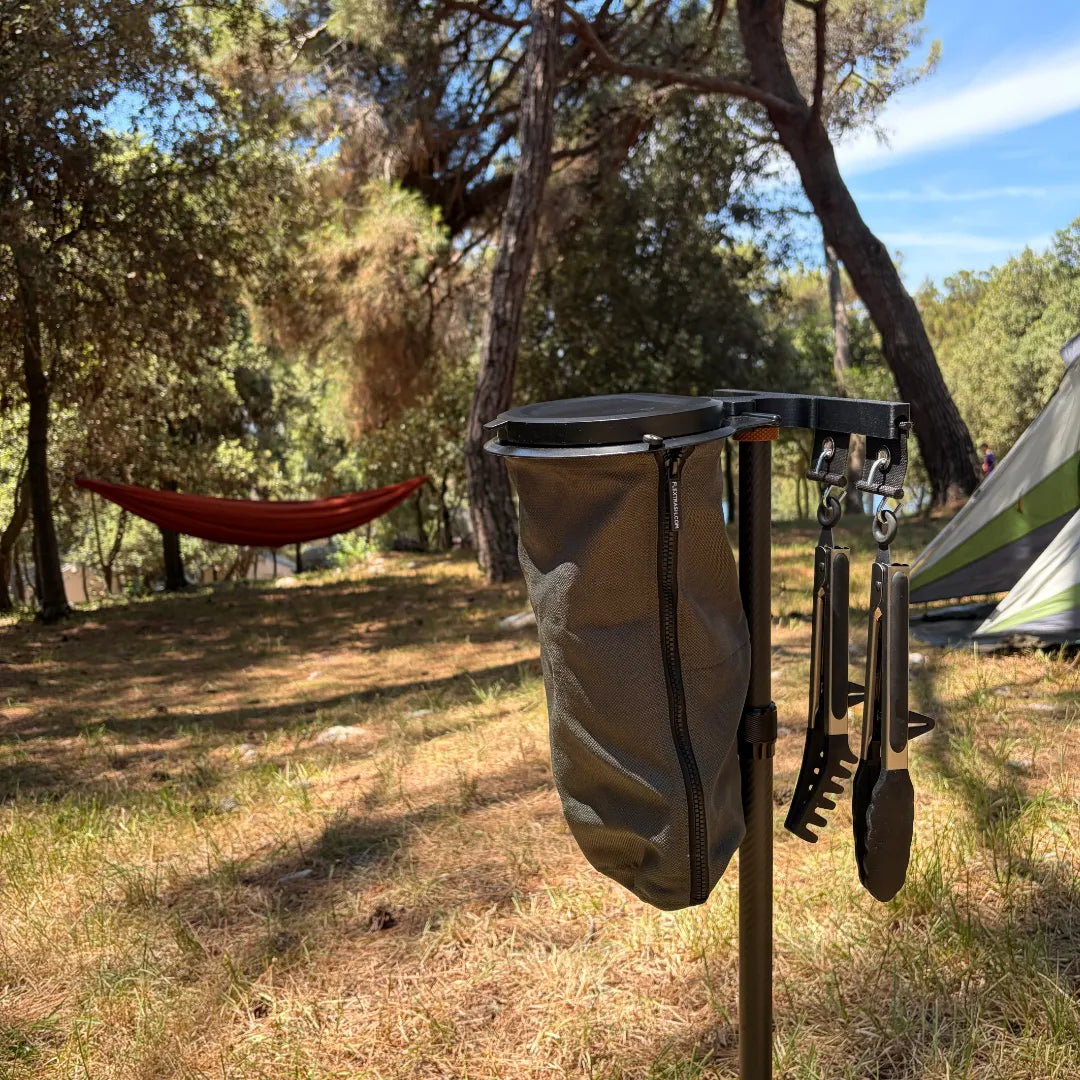 SheltaFlex FlexDock Duo Komplettsystem mit Flextrash Abfallbehälter neben einem Zelt im sonnigen Sommerwald, im Hintergrund eine Hängematte.