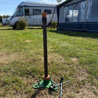 SheltaFlex FlexMount Base und eingesteckte Carbon-Teleskopstange auf einer Wiese, vorbereitet für die Aufnahme eines Adapters.