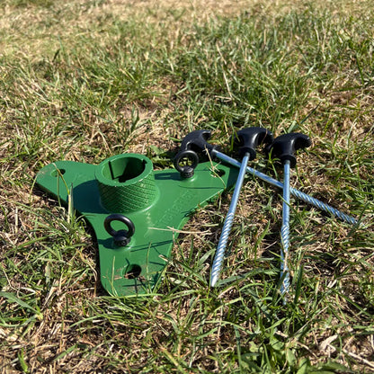 SheltaFlex FlexMount Base mit Erdanker, aufgestellt auf einer Wiese.