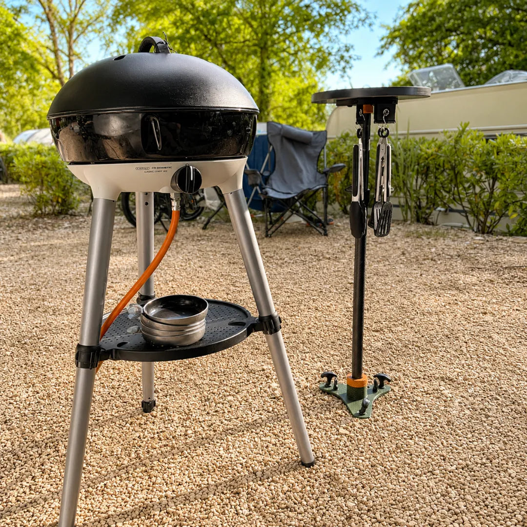 SheltaFlex TableTower mit Grillwerkzeug unter der Tischplatte neben einem Cadac Grill – platzsparende Grillstation für Camping und Outdoor im Sommer.