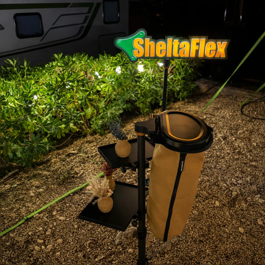 SheltaFlex TrashDock mit Flextrash Abfallbehälter und FlexTray an der Carbon-Teleskopstange bei Nacht – im Hintergrund das beleuchtete SheltaFlex Logo am Campingplatz.