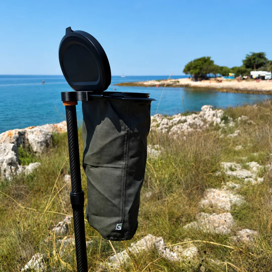 SheltaFlex TrashDock mit montiertem Flextrash Abfallbehälter an der Carbon-Teleskopstange am Meer – platzsparende Mülllösung für Camping und Vanlife.