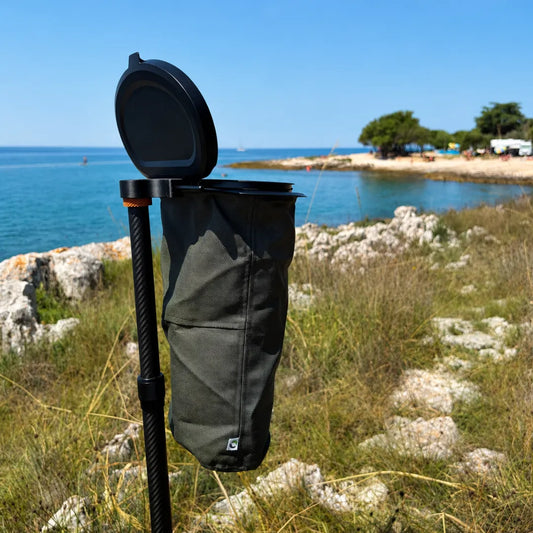 SheltaFlex TrashDock mit montiertem Flextrash Abfallbehälter an der Carbon-Teleskopstange am Meer – platzsparende Mülllösung für Camping und Vanlife.